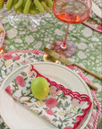 Dining table setting with floral tablecloth, plates, cutlery, and fruit.