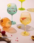 Orange, yellow and teal goblets with cocktails and fresh fruit