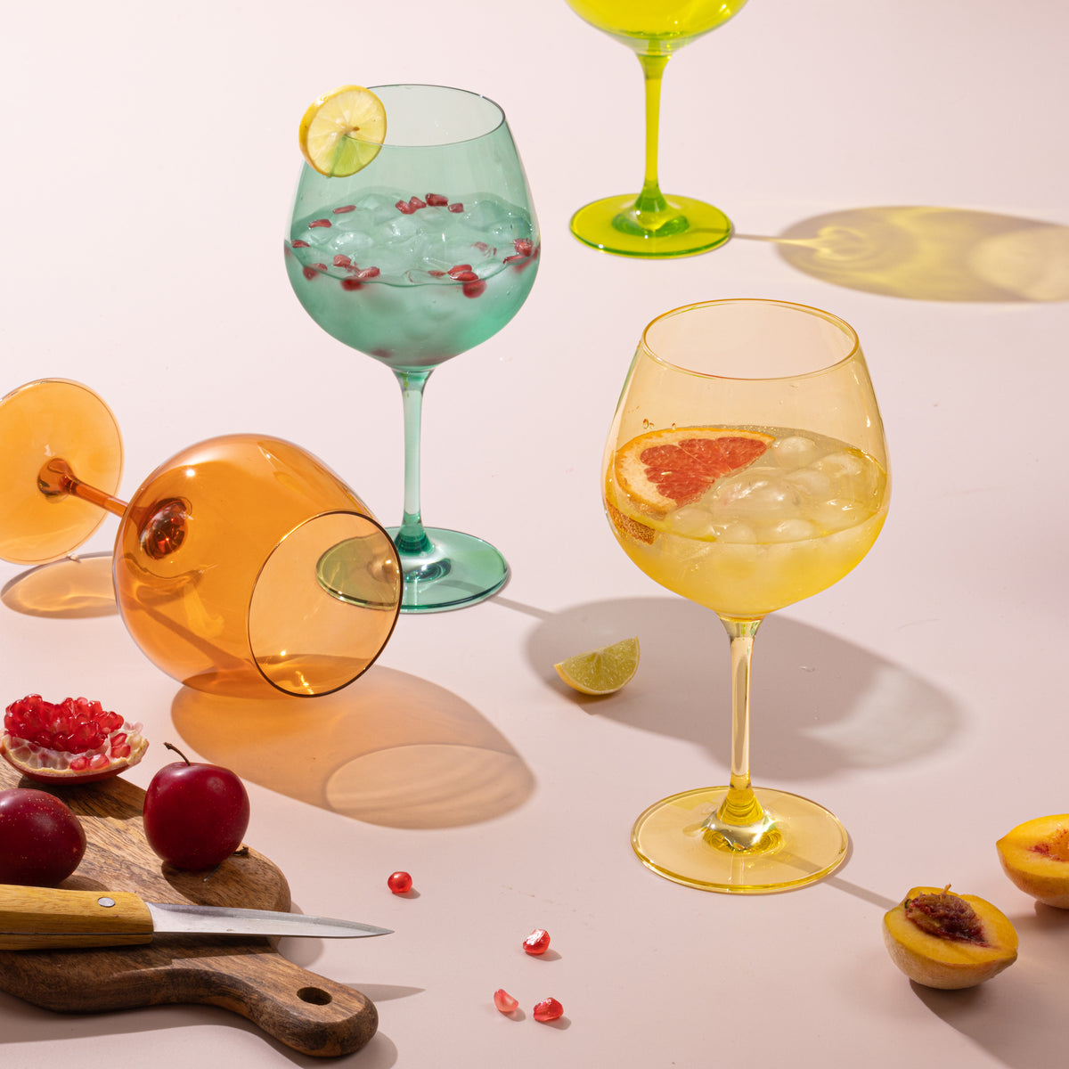 Orange, yellow and teal goblets with cocktails and fresh fruit